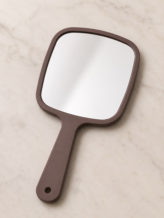 A hand mirror resting on a marble surface